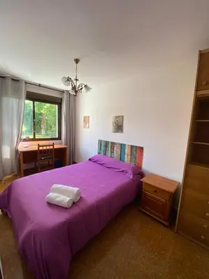 a bedroom with a purple bed with a table and a window at Piso grande y muy luminoso in Santiago de Compostela
