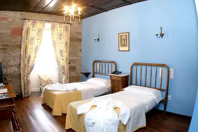 two beds in a room with blue walls and a window at Hotel Monumento Pazo do Castro in O Barco de Valdeorras