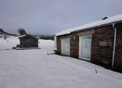 a snow covered yard next to a brick building at Apartamentos Lucio Rodinso in Castroverde