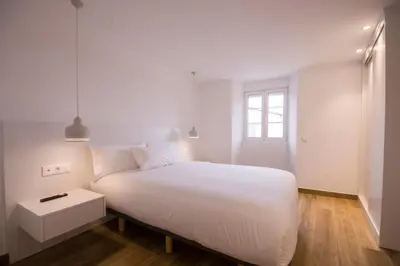a white bedroom with a white bed and a window at Apartamentos Lucio Rodinso in Castroverde