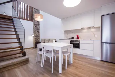 a kitchen and dining room with a white table and chairs at Apartamentos Lucio Rodinso in Castroverde