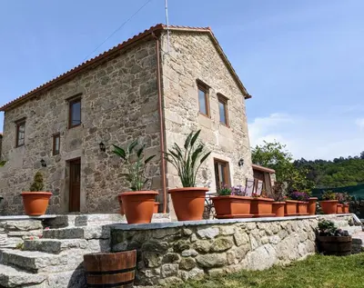 a stone house with potted plants on a stone wall at El cobijo de Soar ¡Casa rural completa! in Moraña