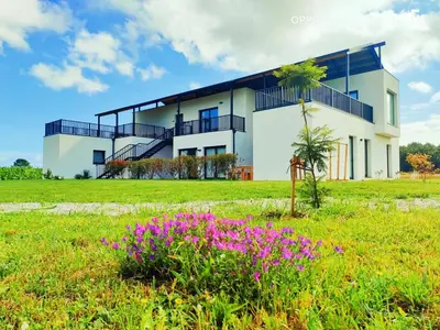a white house with purple flowers in a field at Anam Cara House in Serantes