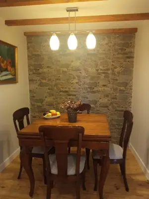 a dining room table with chairs and a stone wall at O Noso Lar - RIBEIRA SACRA in Nogueira de Ramuin