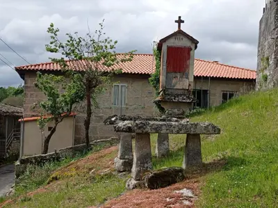 a cross on top of a stone bench in front of a building at O Noso Lar - RIBEIRA SACRA in Nogueira de Ramuin
