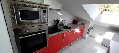 a kitchen with a microwave and a red cabinets at Casa Tarrazo II in Monforte de Lemos