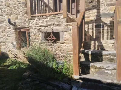 a stone house with a wooden staircase and a window at Apartamento Felicitas en La Casa de Cobos, Ribeira Sacra in Puebla del Brollón