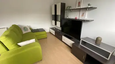 a living room with a green couch and a flat screen tv at A CUARTA RONDA in Melide