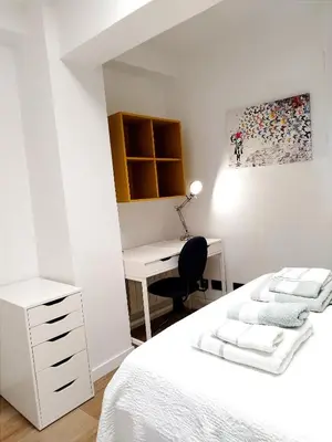 a bedroom with a white bed and a desk at Vivienda Alameda de Santiago in Santiago de Compostela