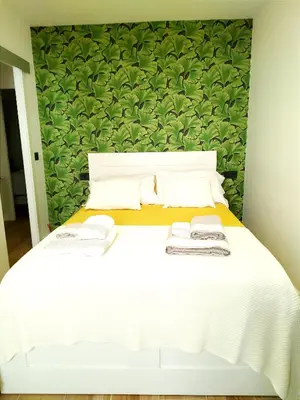 a bedroom with a white bed with a green wall at Vivienda Alameda de Santiago in Santiago de Compostela