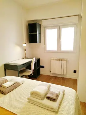 a bedroom with a desk and a bed with towels on it at Vivienda Alameda de Santiago in Santiago de Compostela