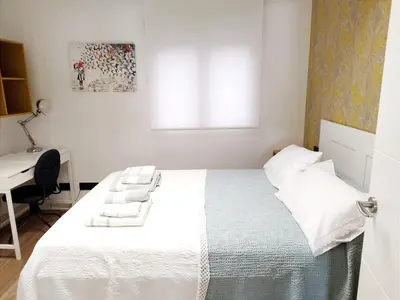 a white bedroom with a bed and a desk at Vivienda Alameda de Santiago in Santiago de Compostela