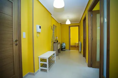 a hallway with yellow walls and a white stool at dpCristal Ático Vistas al Camino in Sarria