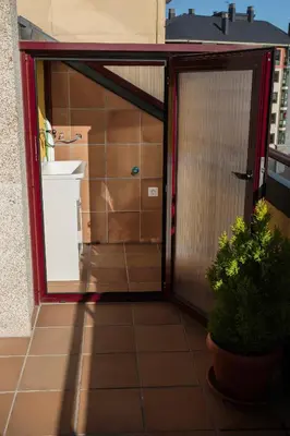 an open door to a balcony with a sink and a refrigerator at dpCristal Ático Vistas al Camino in Sarria