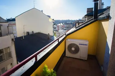 a balcony of a yellow building with a fan at dpCristal Ático Vistas al Camino in Sarria