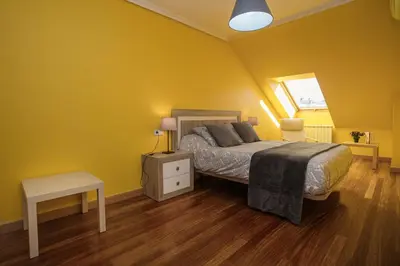 a bedroom with yellow walls and a bed and a table at dpCristal Ático Vistas al Camino in Sarria