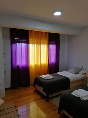 two beds in a room with purple and yellow curtains at Lar de Yago - Casa in Barreiros