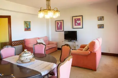 a living room with a table and pink furniture at Playa Miño Sombreu in Miño