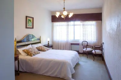 a bedroom with a large white bed and a chandelier at Playa Miño Sombreu in Miño