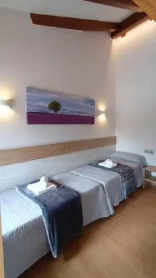 two beds in a room with a painting on the wall at Hostal A Cantina de Renche in Renche