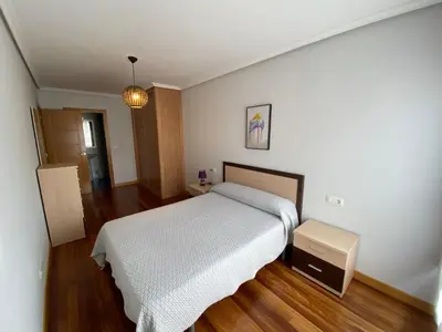 a bedroom with a white bed and a wooden floor at dpCristal LikeHome in Sarria