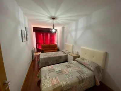 two beds in a room with a red window at dpCristal LikeHome in Sarria
