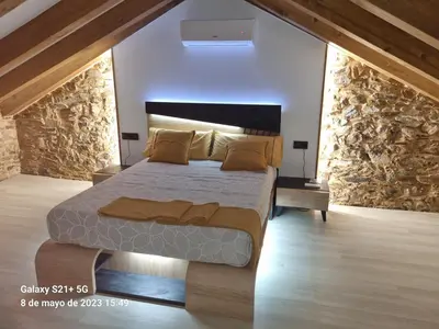 a bedroom with a large bed and a stone wall at Casa Grilo in Monforte de Lemos
