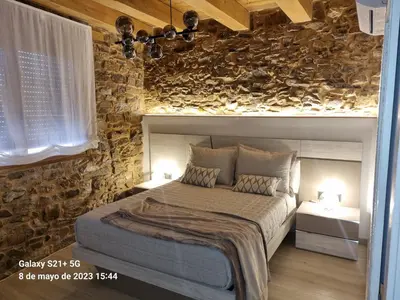 a bedroom with a bed and a stone wall at Casa Grilo in Monforte de Lemos