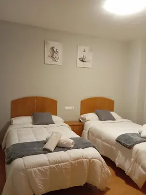 a bedroom with two beds and two pictures on the wall at Pensión Abeledo in Sarria