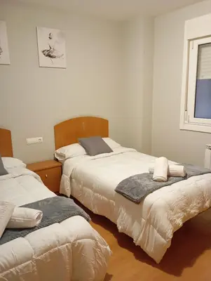 a bedroom with two beds and a window at Pensión Abeledo in Sarria