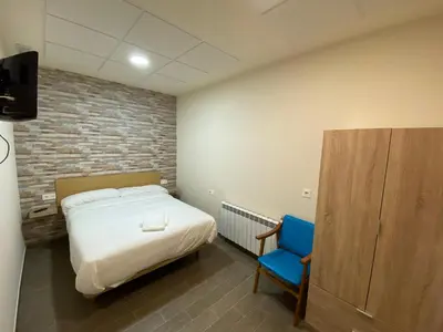 a bedroom with a bed and a blue chair at dpCristal El Rinconcito in Sarria