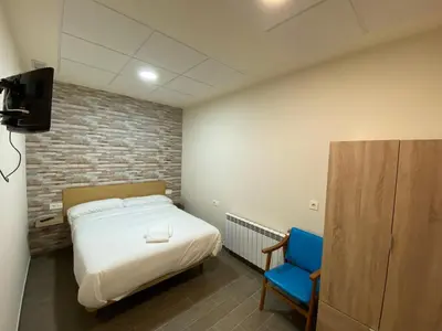 a bedroom with a bed and a blue chair at dpCristal El Rinconcito in Sarria