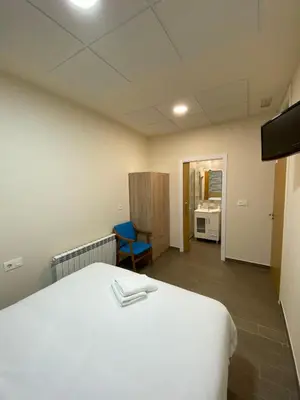 a room with a white bed and a blue chair at dpCristal El Rinconcito in Sarria