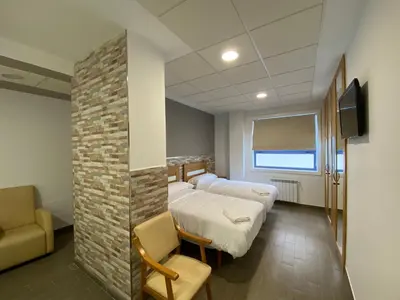 a hospital room with two beds and a couch and a tv at dpCristal El Rinconcito in Sarria