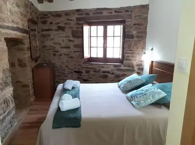a bedroom with a large bed with towels on it at O Busto Aldea Rural in A Pobra do Brollon