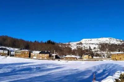 a snow covered field with houses and a mountain at O Busto Aldea Rural in A Pobra do Brollon