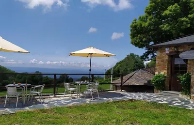 a patio with a table and chairs and an umbrella at O Busto Aldea Rural in A Pobra do Brollon