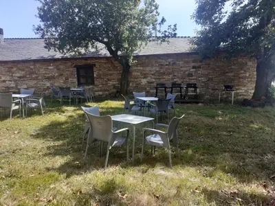 a group of tables and chairs in front of a brick building at O Busto Aldea Rural in A Pobra do Brollon