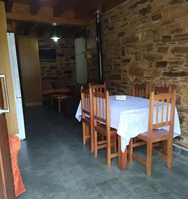 a table and chairs in a room with a stone wall at O Busto Aldea Rural in A Pobra do Brollon