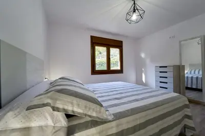 a white bedroom with a bed and a window at O Lar de Lola in Mondariz