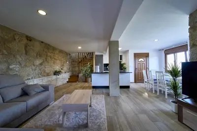 a living room and kitchen with a stone wall at O Lar de Lola in Mondariz