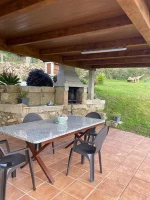 a table and chairs on a patio with a fireplace at O Lar de Lola in Mondariz
