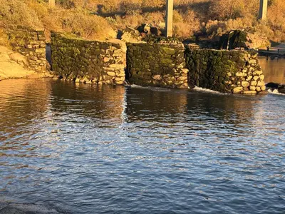a stone wall in the water next to a body of water at Chalet casa con piscina en ARBO Vigo in Arbo