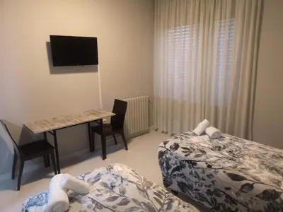 a bedroom with two beds and a desk with a computer at Hostal Conde de Lemos in Ponferrada