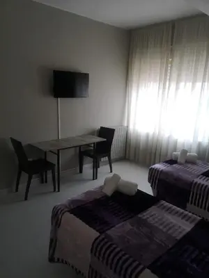a room with two beds and a table and a table and chairs at Hostal Conde de Lemos in Ponferrada