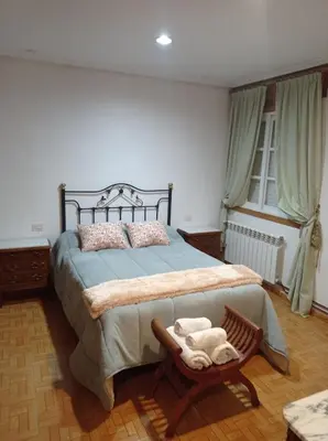 a bedroom with a large bed and a chair at O FOGAR DAS FINAS in Melias