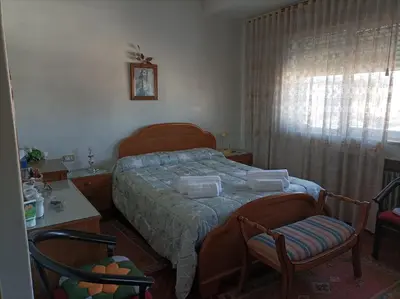 a bedroom with a bed and two chairs and a window at Casa Jesús in Sarria