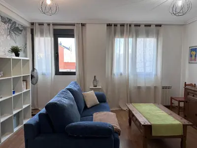 a living room with a blue couch and a table at Apartamento La Emisora in Ponferrada