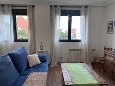 a living room with a blue couch and two windows at Apartamento La Emisora in Ponferrada