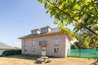 a large brick house with a bench in front of it at Casona con Jacuzzi in Betanzos